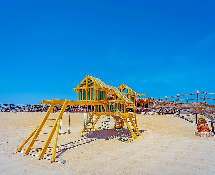 The kids area at Paradise Island, a yellow timber play frame with slides, set back from the water.