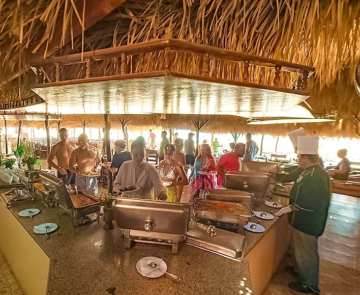 The open buffet under a thatched roof at Paradise Island, guests serving themselves along the counter.