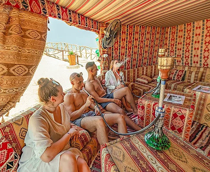 The shisha corner at Paradise Island, a canvas tent hung with rugs and cushions, open to the beach.