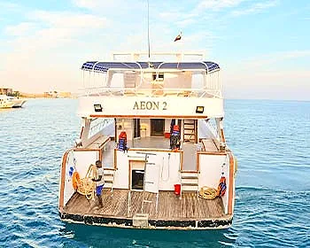 Aeon 2 seen from astern with her bathing platform down and crew on deck.